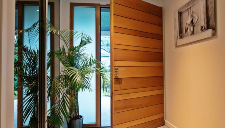 Une porte d'entrée Nativ 2 moderne en bois entre ouverte avec un semi fixe vitré