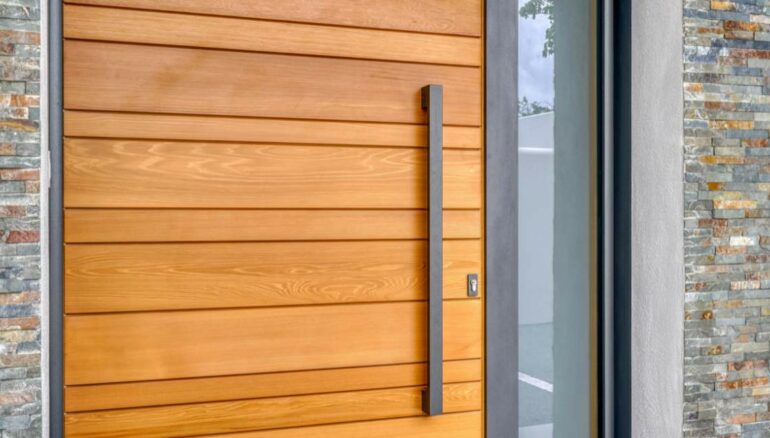 Porte d'entrée en bois Nativ 10 fusion avec une barre de tirage sur façade en pierre