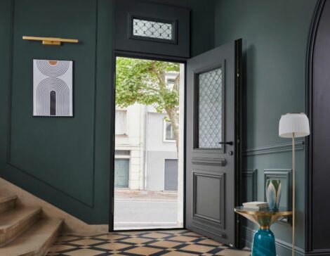 porte d'entrée traditionnelle en aluminium avec un vitrage et une grille intégrée dans une maison ancienne rénovée