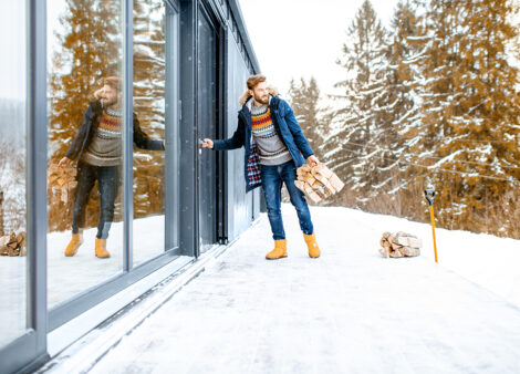 Homme qui entre dans sa maison depuis sa terrasse couverte de neige.