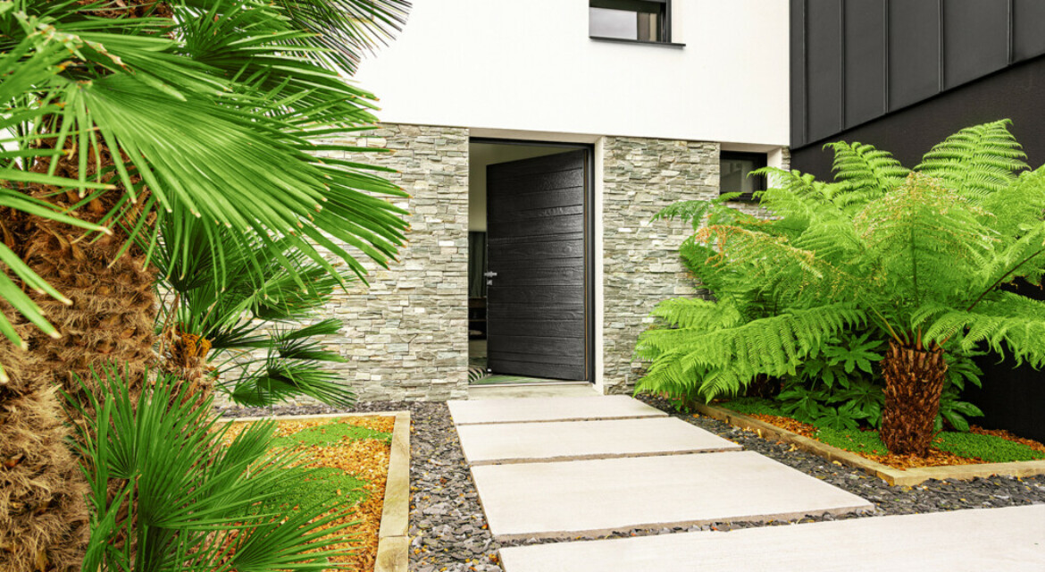 Maison moderne avec beaucoup de verdure et une porte d'entrée en bois Nativ Zilten