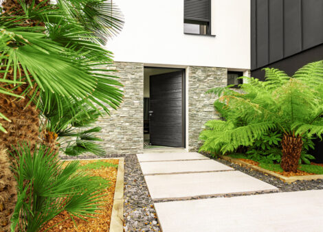 Maison moderne avec beaucoup de verdure et une porte d'entrée en bois Nativ Zilten