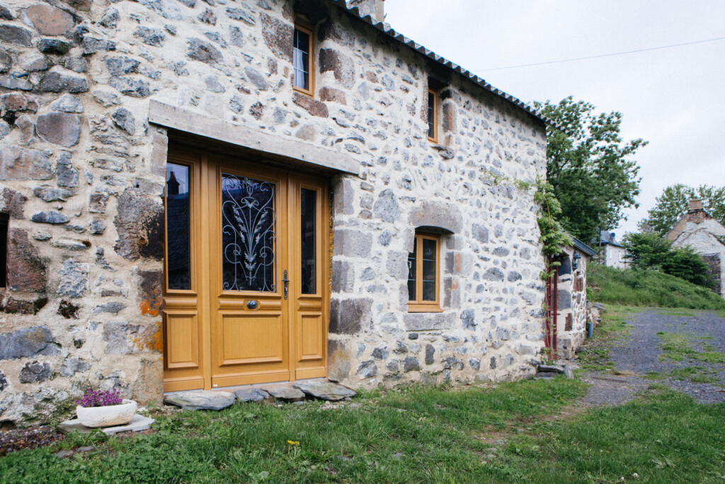 Porte d’entrée en bois avec moulures et grille sur demeure ancienne 