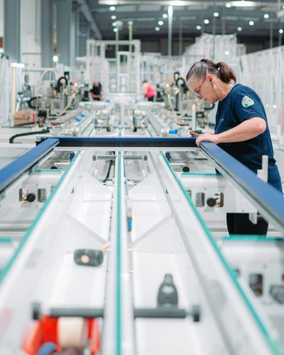 femme au sein d'une usine de production en trains de travailler un cadre de porte d'entrée en aluminium