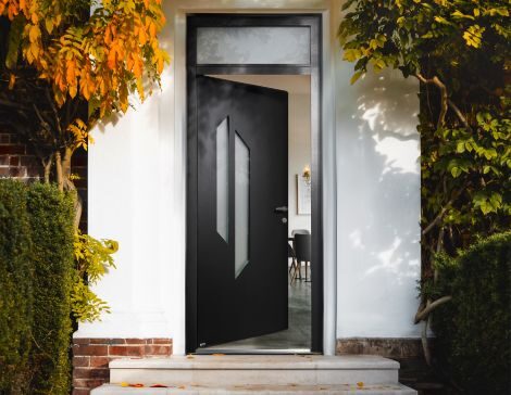 porte d'entrée en aluminium noire avec un design contemporain et un vitrage et une imposte sur une maison blanche