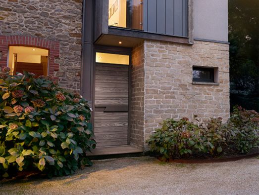 Porte d'entrée en bois Accoya® sur maison en pierre.