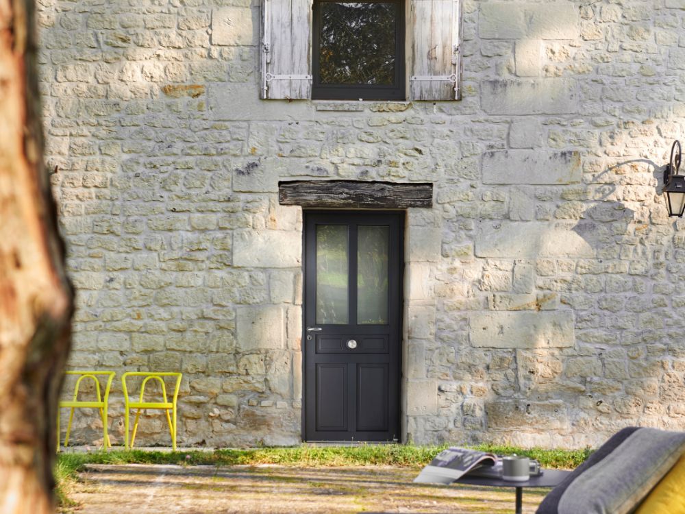 maison de campagne en pierre avec une porte d'entrée en PVC vitrée au style classique