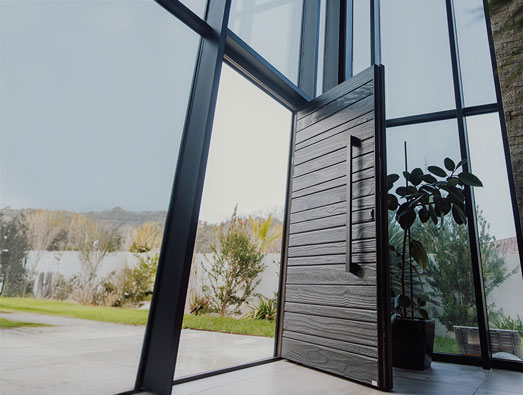 Porte d'entrée moderne avec grand vitrage donnant sur l'extérieur