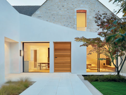 porte d'entrée en bois sur une villa moderne blanche avec du parement de pierre