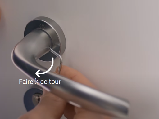 une personne qui démonte une poignée de porte d'entrée à l'aide d'une clé de déblocage